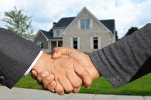 Two men shaking hands in front of house