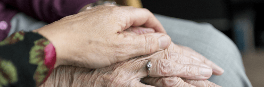 woman placing hands on senior woman's hands