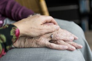 woman placing hands on top of senior woman's hands